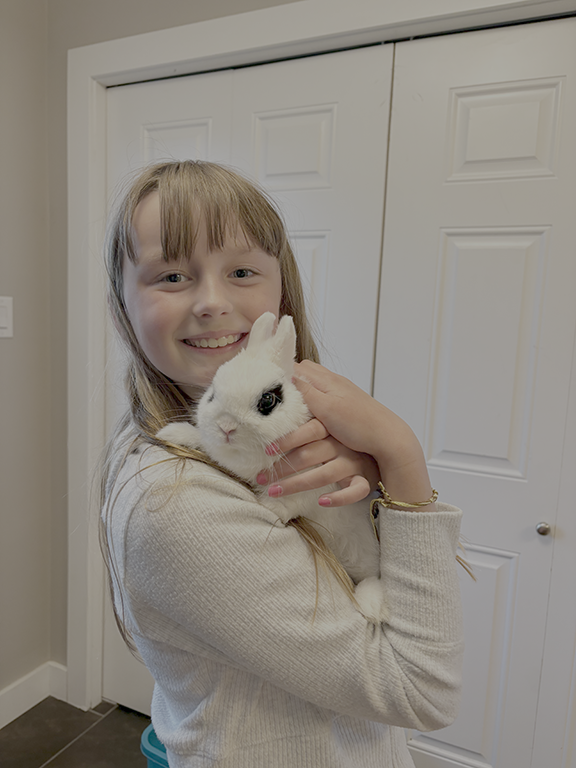 A girl happily holding her adopted white rabbit